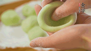 將均分的艾草面團搓成圓，挖一個窩，放入餡心，再搓成圓。