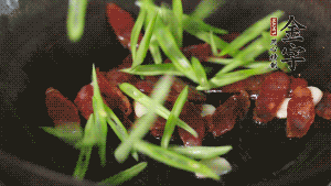 先后下香腸片、四季豆絲均勻翻炒，加適量清水燜煮一下。