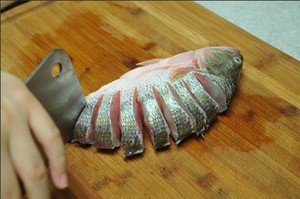 將鱸魚清洗干凈，從脊椎處切斷至腹部，腹部保留1cm左右不要切斷。