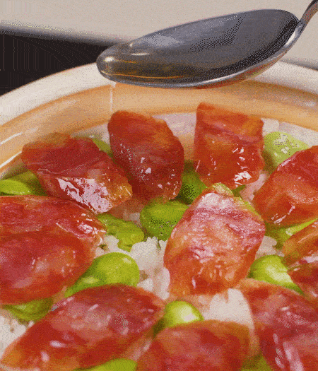 大米出現(xiàn)小孔時(shí)開(kāi)蓋放香腸，往鍋邊淋入少許油，再燜煮8~10分鐘左右。