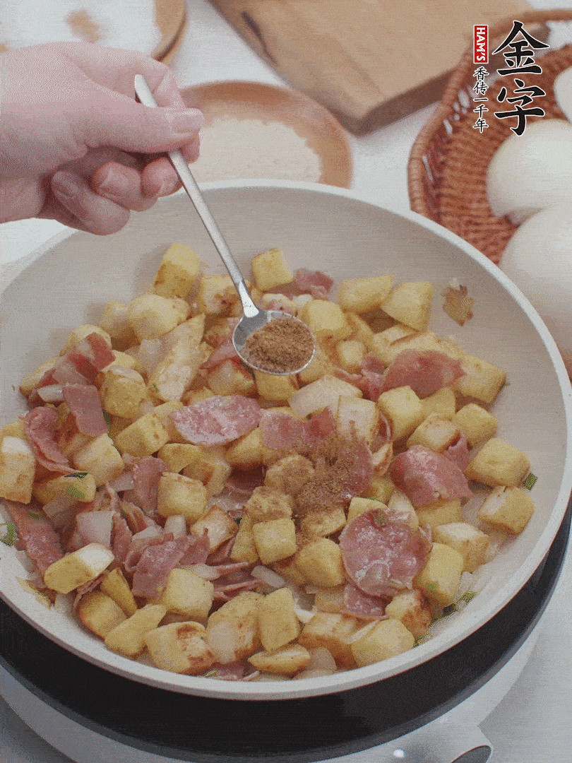 起鍋少油，煸香洋蔥丁、蔥白，加入金字培根火腿翻炒幾下，再加入饅頭丁、1小勺孜然粉、少許鹽翻炒均勻并鋪平。